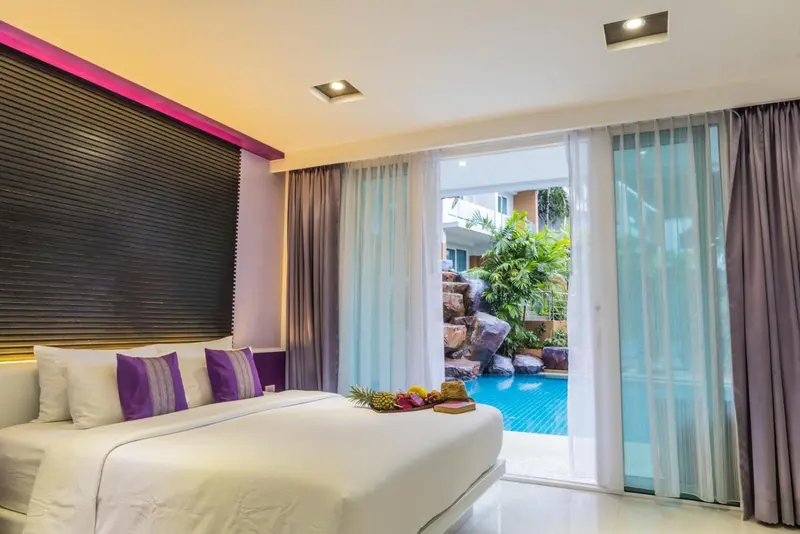 Une chambre lumineuse avec un lit fait et vue sur une piscine.