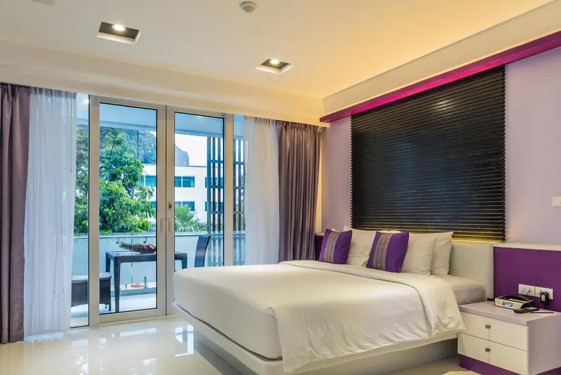 Une chambre lumineuse avec un grand lit et un accès à une terrasse.