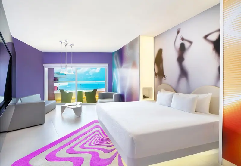 Une chambre moderne avec un grand lit blanc et une vue sur la mer.