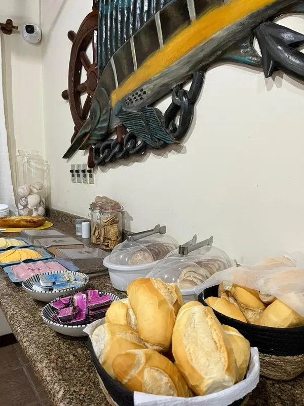 Une table garnie de viennoiseries et de confitures est présentée en premier plan.