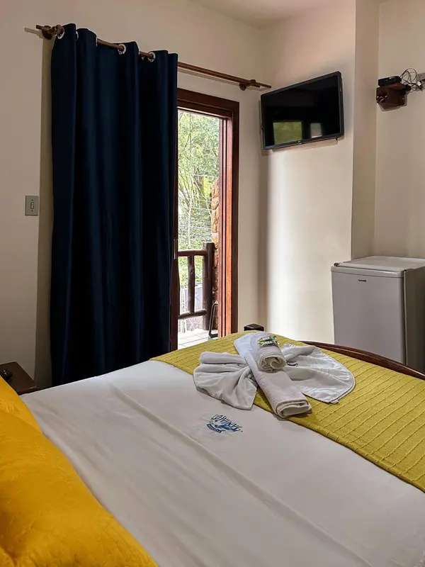 Une chambre lumineuse avec un lit recouvert d'une couverture jaune et des serviettes décoratives.