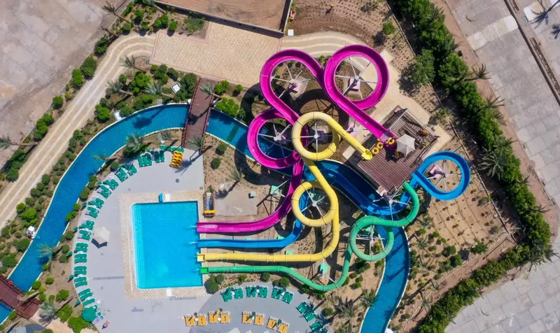 Vue aérienne d'un parc aquatique avec des toboggans colorés et des piscines.