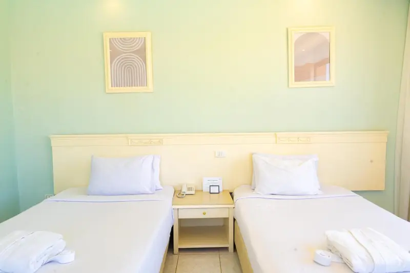 Une chambre lumineuse avec deux lits simples et une décoration murale.