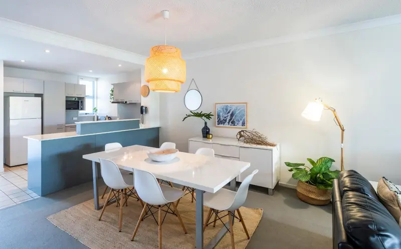 Une salle à manger lumineuse avec une table et des chaises blanches.
