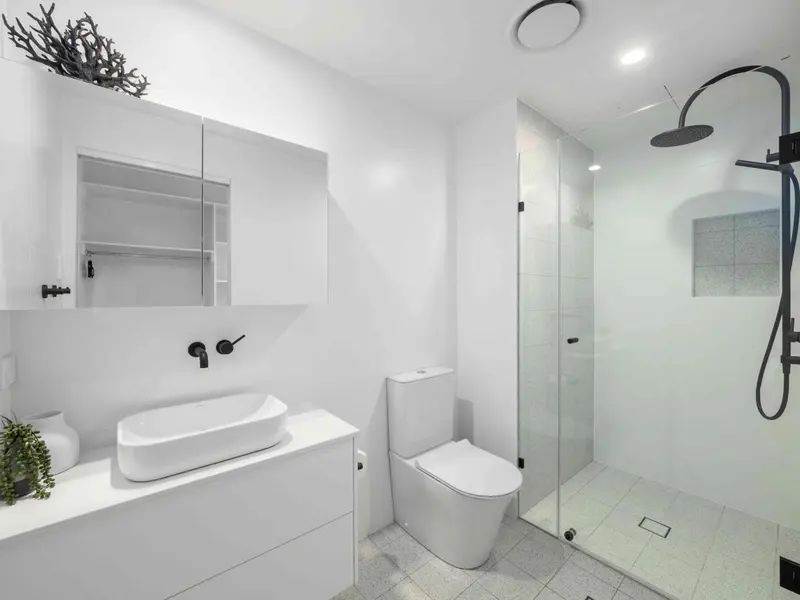 Une salle de bain moderne avec douche à l'italienne et vasque blanche.