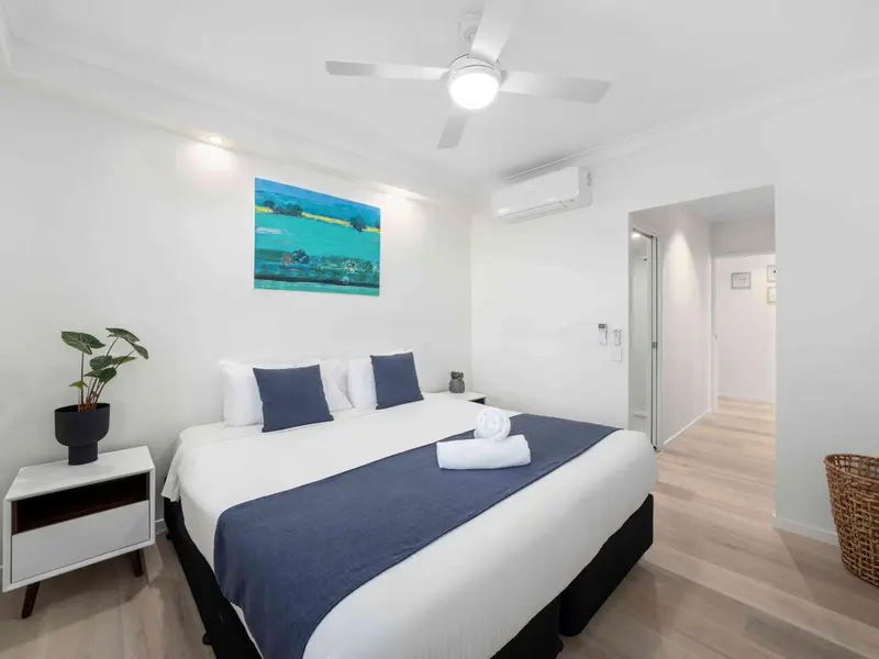 Une chambre lumineuse avec un grand lit recouvert d'une courtepointe bleue.
