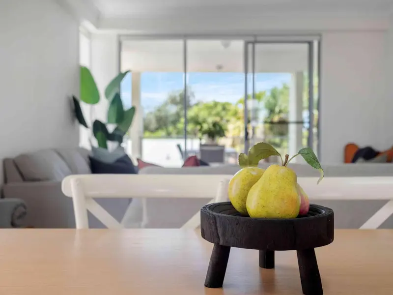 Une table en bois clair présente des fruits dans un intérieur lumineux.