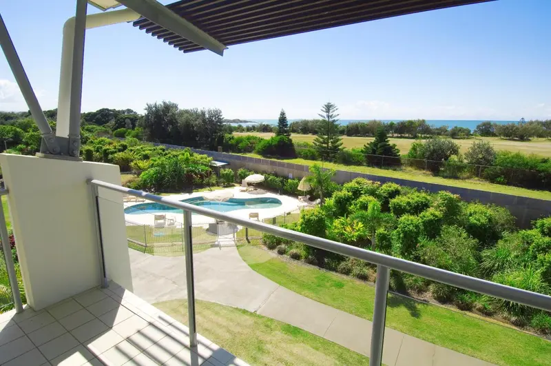 Vue d'un balcon donnant sur une piscine et un paysage verdoyant.