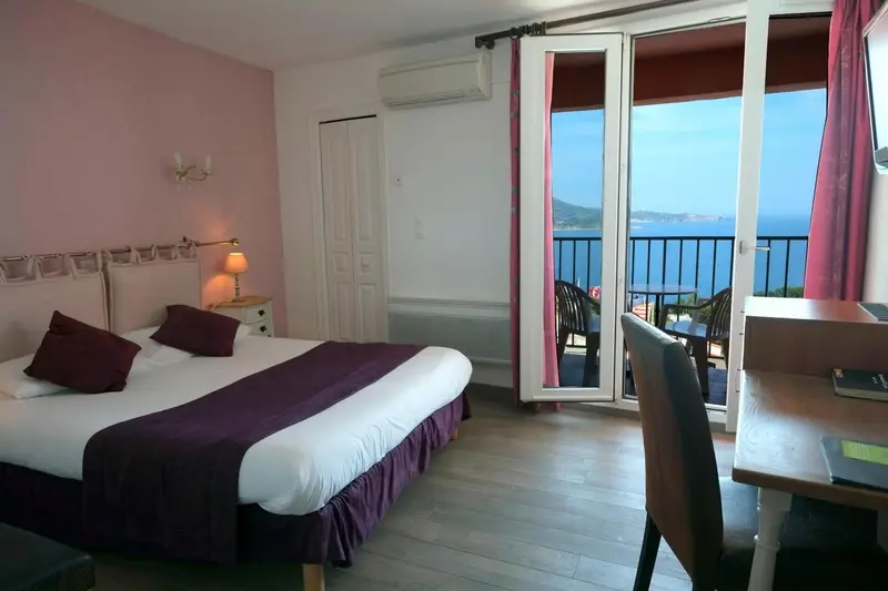 Une chambre lumineuse s'ouvre sur une terrasse avec vue sur la mer.