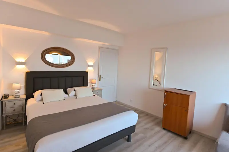 Une chambre lumineuse avec un grand lit et un décor sobre.