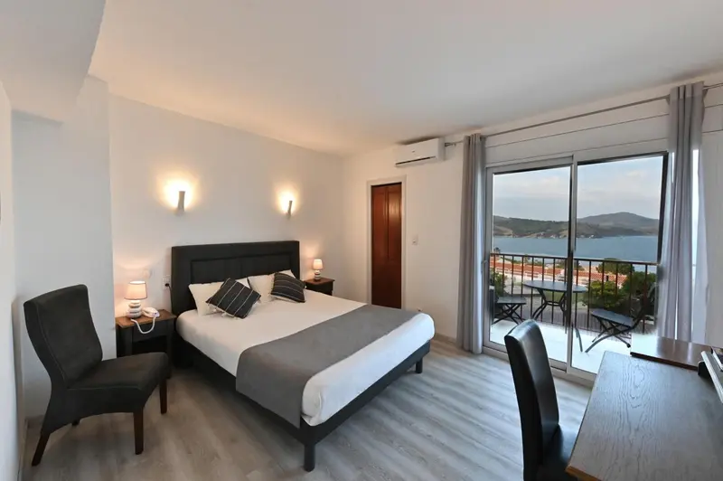 Chambre lumineuse avec un grand lit et vue sur la mer.