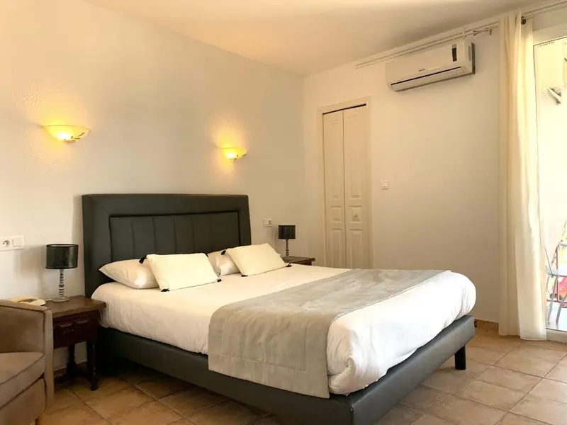 Une chambre lumineuse avec un grand lit recouvert d'une courtepointe blanche.