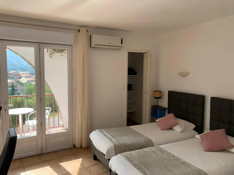 Une chambre lumineuse avec un lit double et un balcon offrant une vue sur la ville.