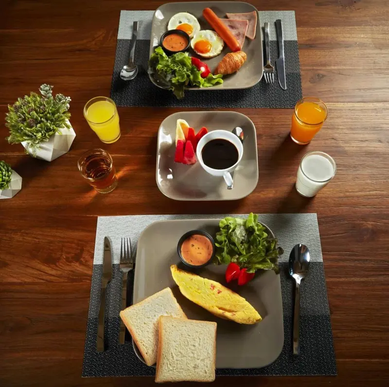 Une table est dressée avec plusieurs plats pour le petit-déjeuner.