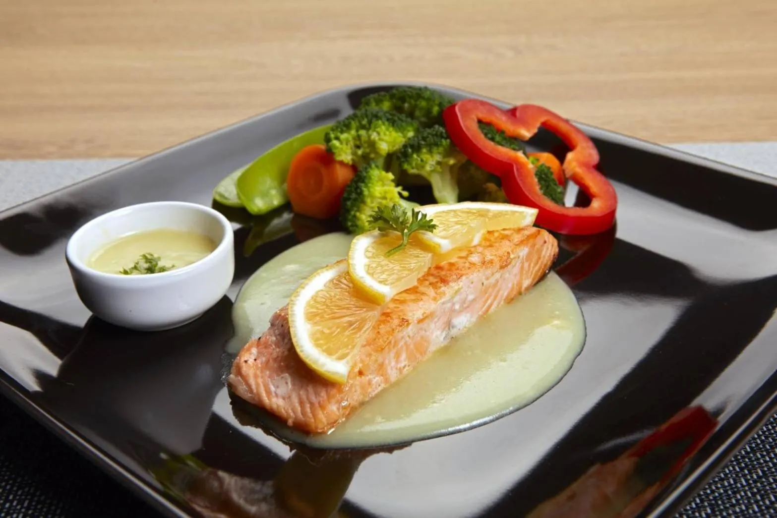 Un plat de poisson servi avec des légumes et une sauce.