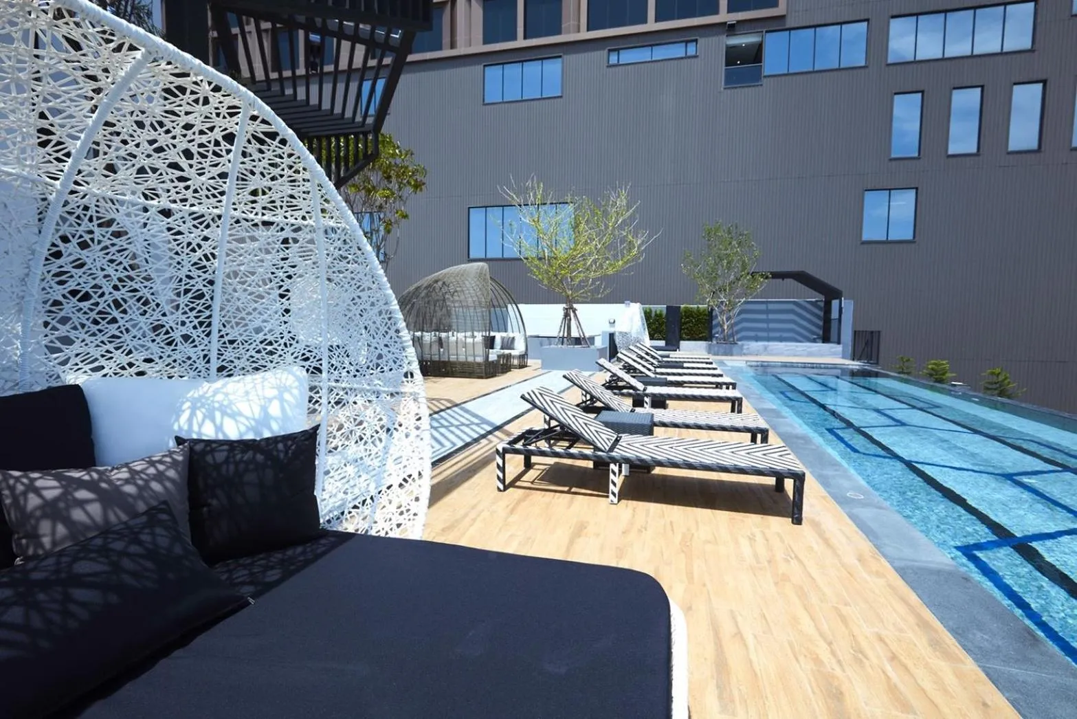 Terrasse aménagée avec des transats et des salons de jardin près d'une piscine.