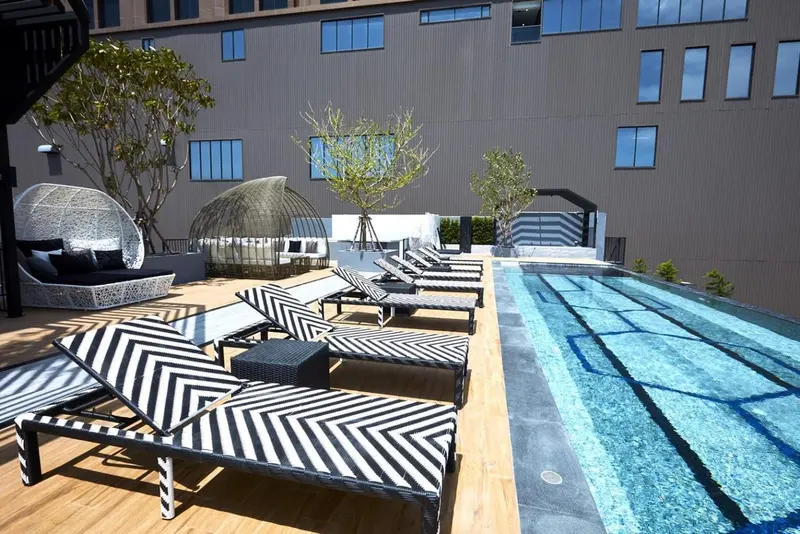 Transats rayés noirs et blancs disposés autour d'une piscine rectangulaire.