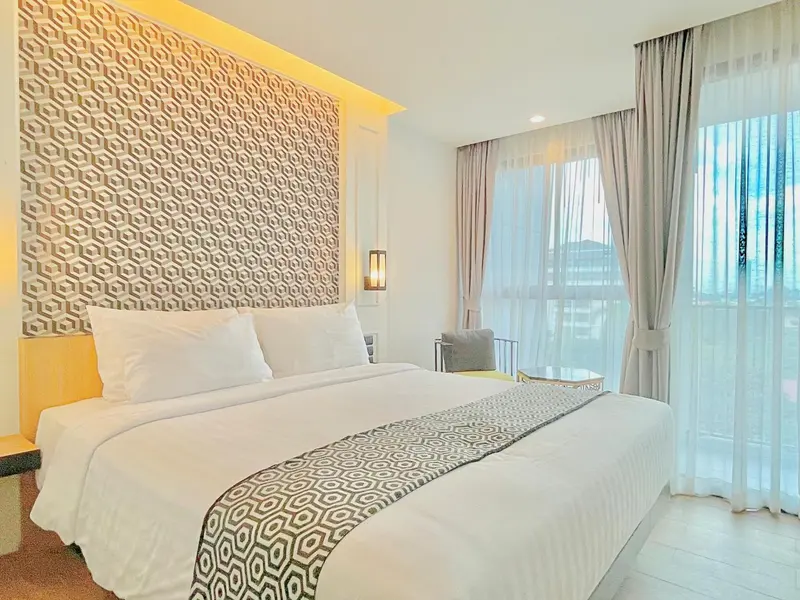 Une chambre lumineuse avec un grand lit et une fenêtre donnant sur l'extérieur.