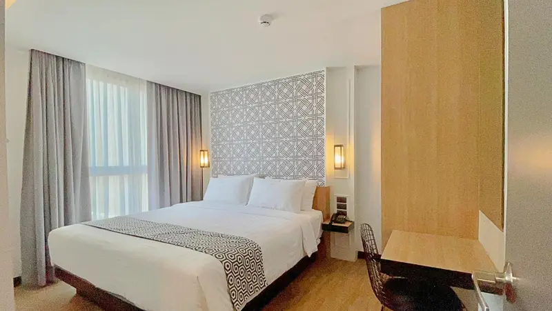 Une chambre d'hôtel lumineuse avec un grand lit et un bureau.