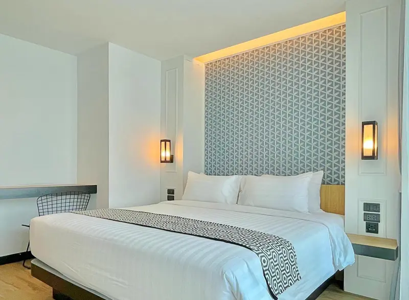 Une chambre lumineuse avec un grand lit recouvert d'une courtepointe blanche et grise.