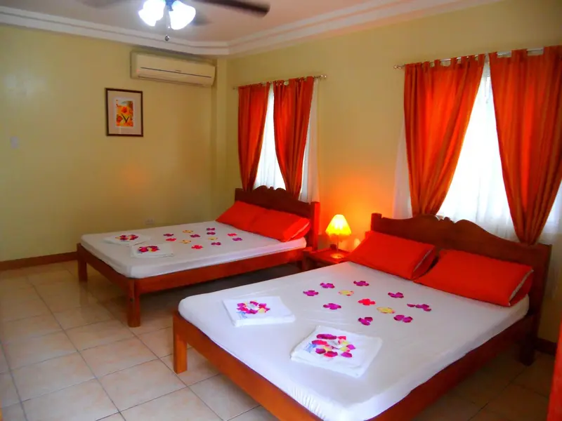 Une chambre lumineuse avec deux lits décorés de fleurs et de serviettes.