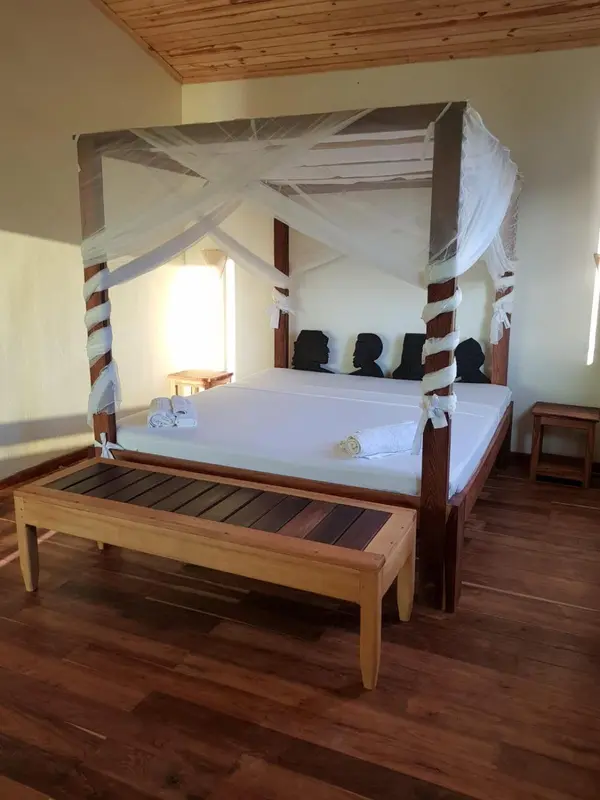 Une chambre lumineuse avec un grand lit à baldaquin en bois.
