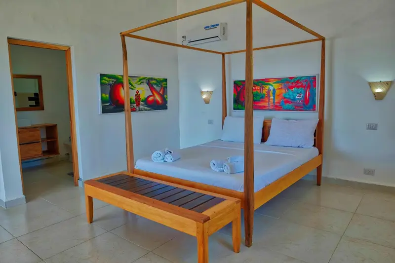 Une chambre lumineuse avec un grand lit à baldaquin et des œuvres d'art colorées.