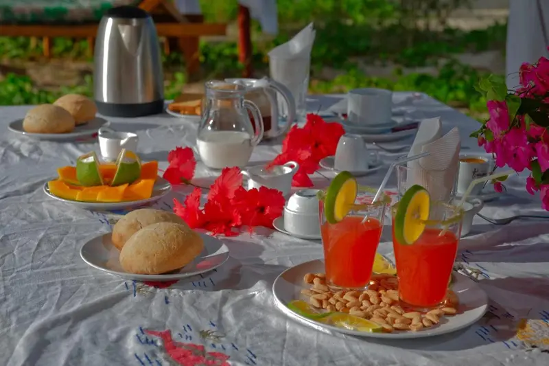 Une table est dressée avec des viennoiseries, des fruits frais et des boissons.