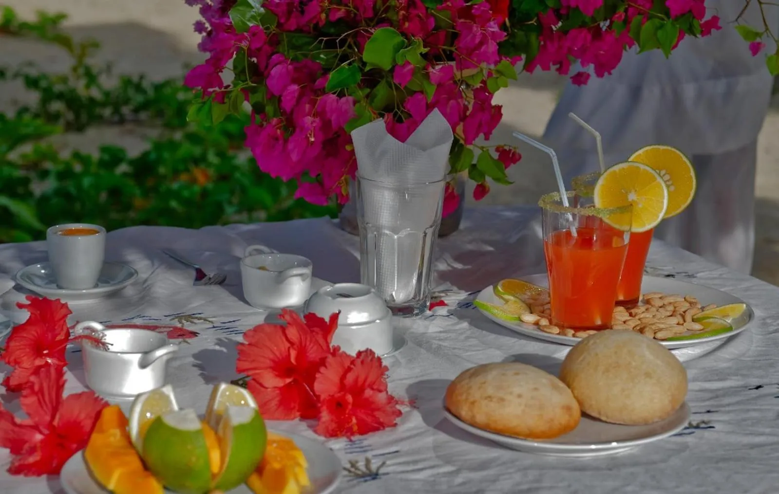 Une table est dressée avec des boissons colorées, des pâtisseries et des fruits.