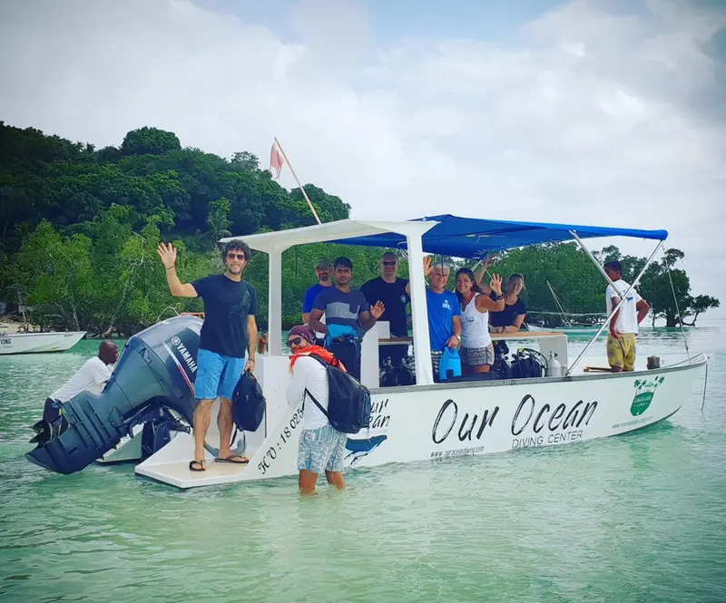 Un bateau de passagers navigue sur une eau turquoise près d'une île verdoyante.