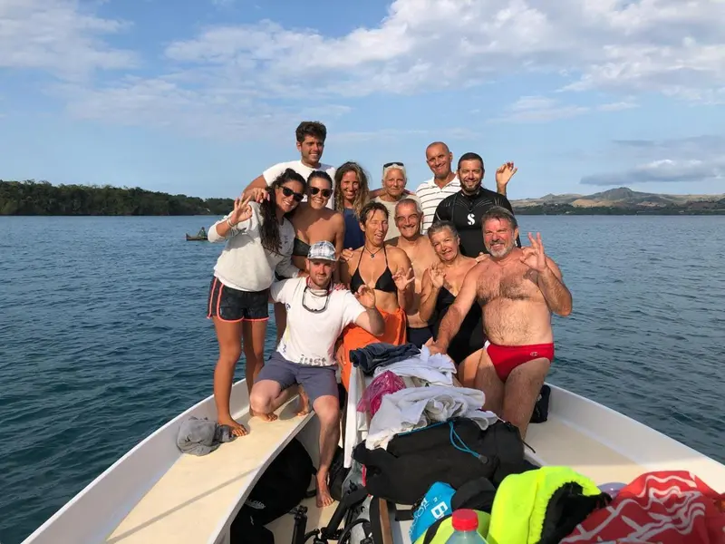 Groupe de personnes souriantes posant sur la proue d'un bateau en mer.