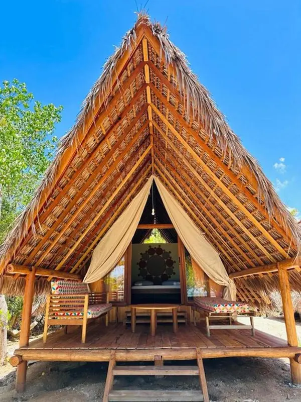 Petite cabane de plage au toit de chaume avec une terrasse en bois.