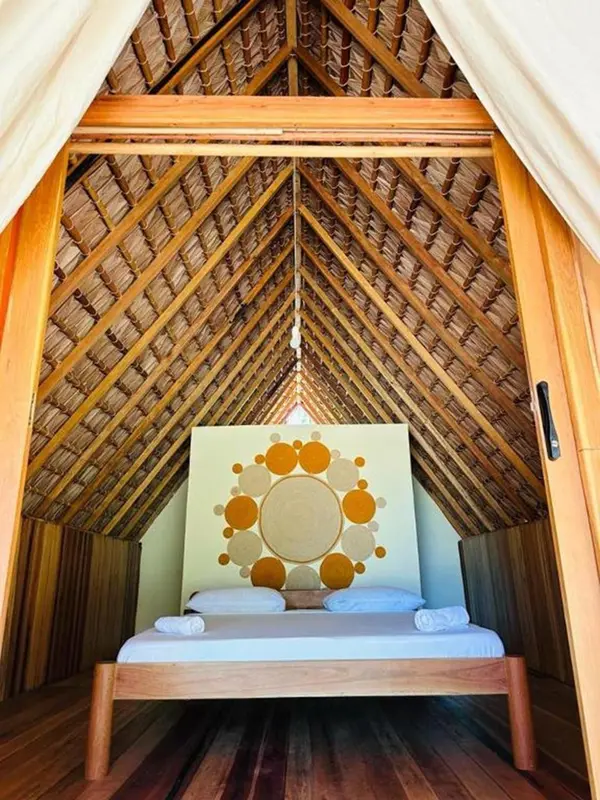 Un lit simple dans une chambre au toit de chaume décoré.