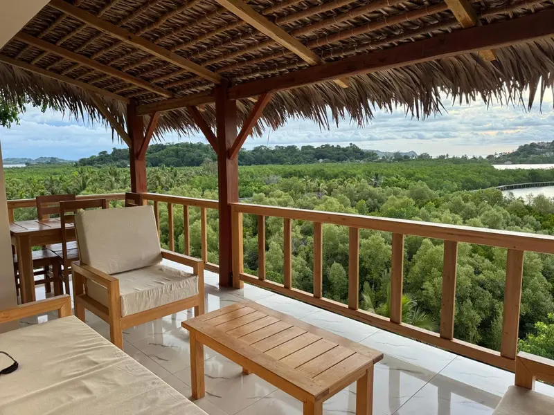 Terrasse en bois avec mobilier d'extérieur donnant sur une végétation luxuriante.