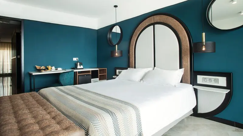 Une chambre moderne avec un grand lit et un mur bleu turquoise.