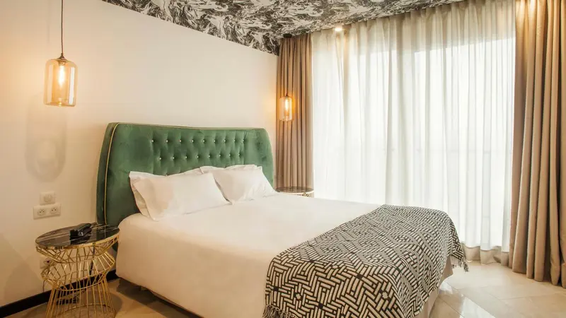 Une chambre lumineuse avec un grand lit recouvert d'une courtepointe.