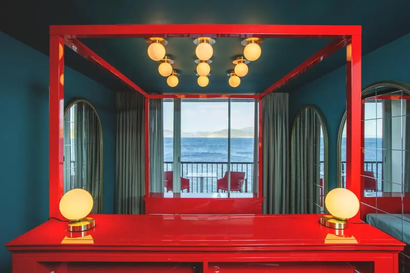 Lit rouge vif dans une chambre avec vue sur la mer.