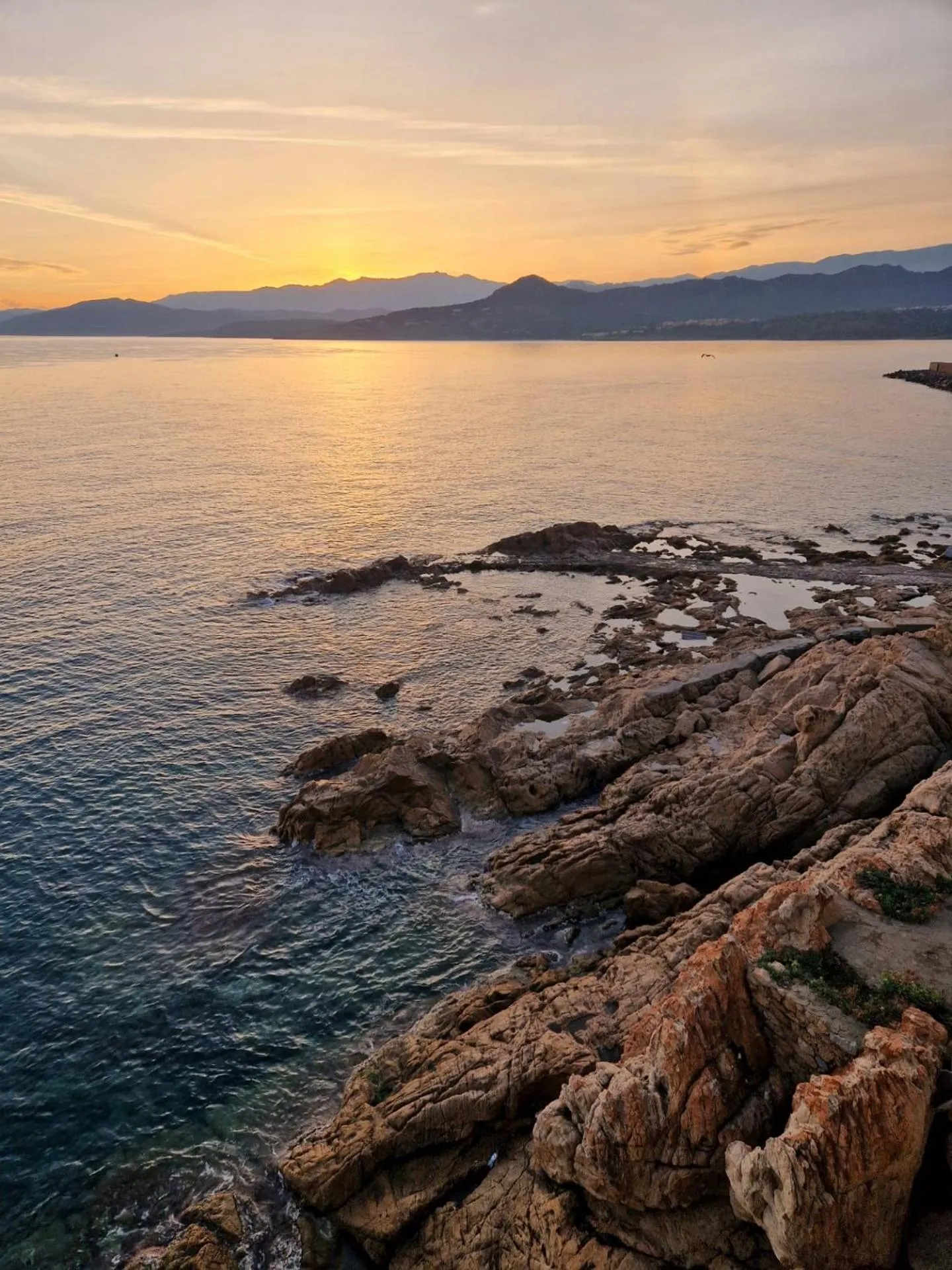 Coucher de soleil sur une côte rocheuse avec vue sur la mer.
