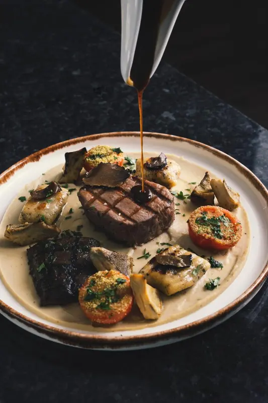Assiette de viande grillée nappée d'une sauce foncée, accompagnée de légumes et de champignons.