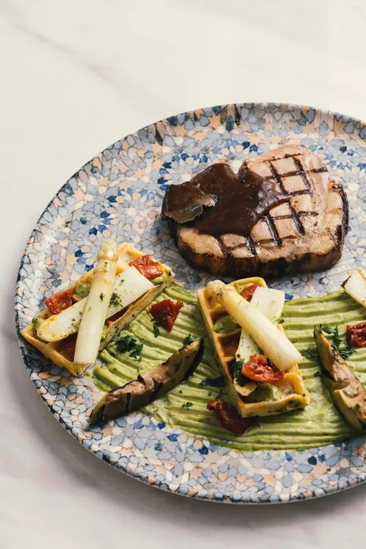 Assiette de viande grillée accompagnée de légumes et d'une sauce.