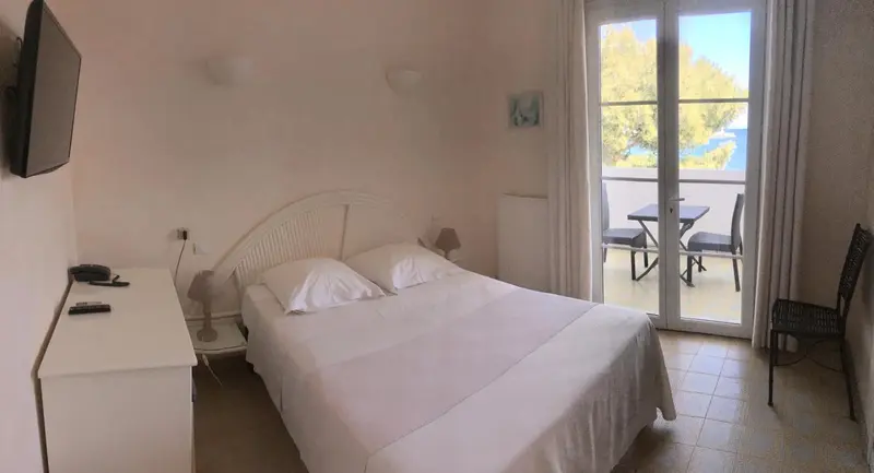 Une chambre lumineuse avec un lit double et un accès à une terrasse.