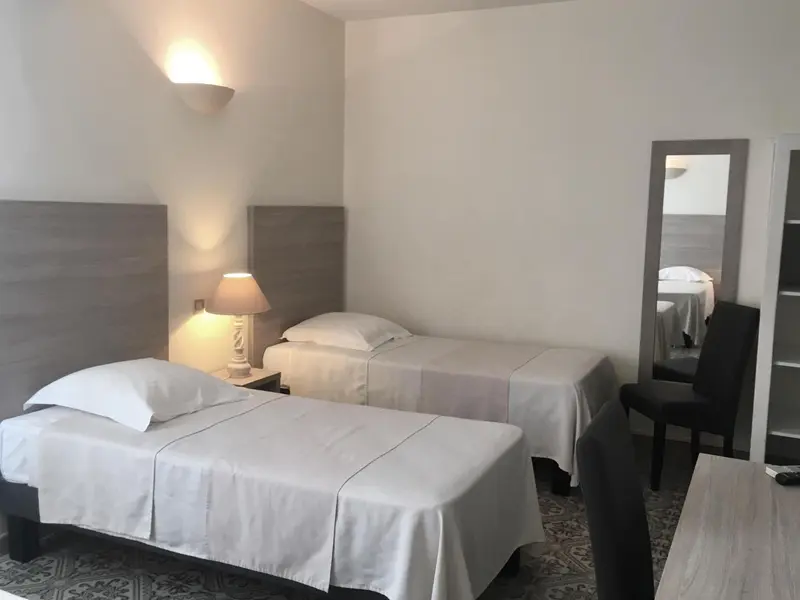 Une chambre avec deux lits simples et un miroir.