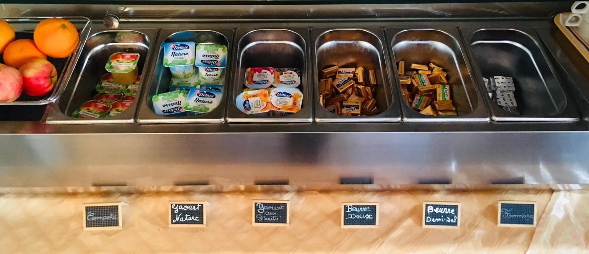 Présentation de yaourts, de confitures et de viennoiseries sur un buffet.