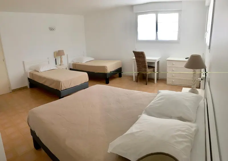 Une chambre lumineuse avec deux lits simples et un bureau.