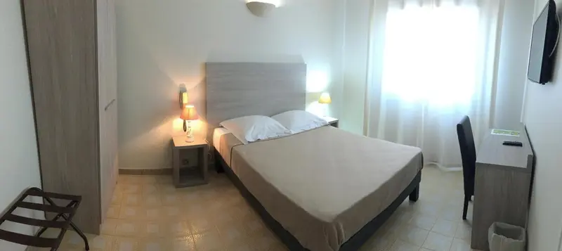 Une chambre lumineuse avec un grand lit et un bureau.