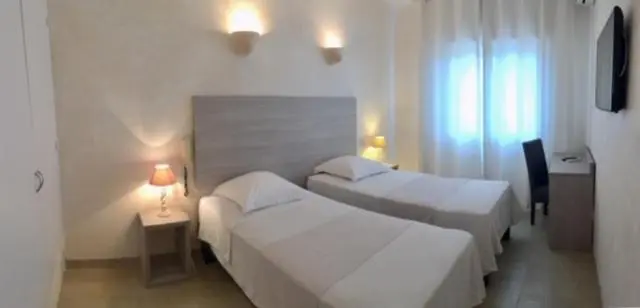 Une chambre lumineuse avec deux lits simples et des lampes de chevet.