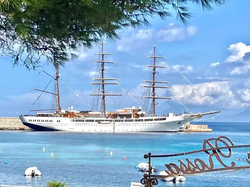 Un grand voilier blanc est amarré dans une baie turquoise.