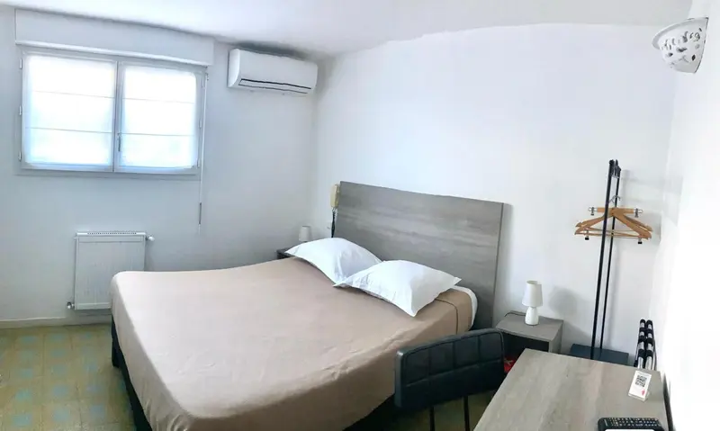 Une chambre lumineuse avec un lit double et un bureau.