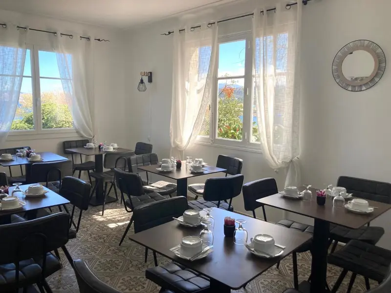 Une salle lumineuse avec des tables dressées pour le petit-déjeuner.