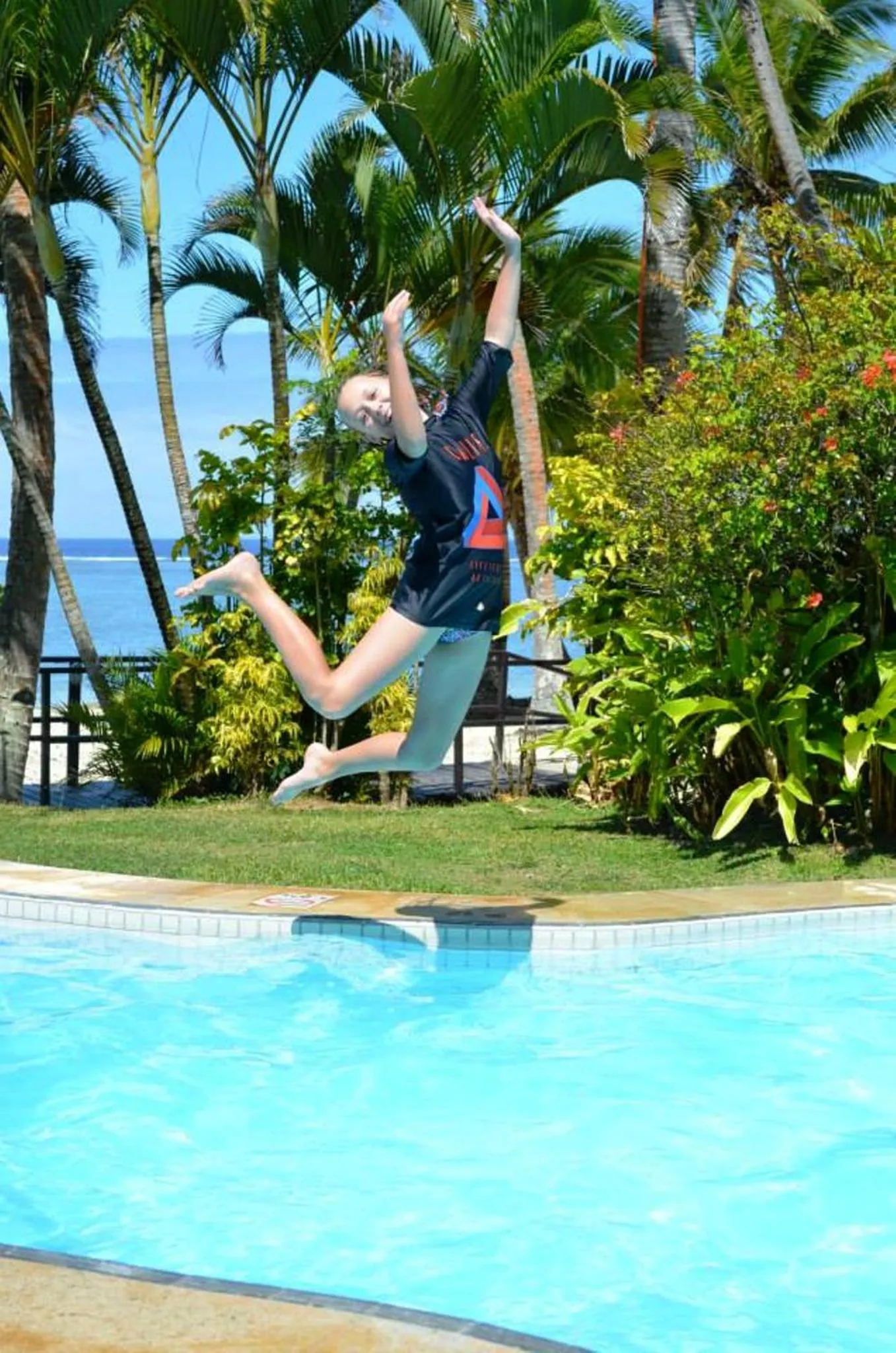 Une personne saute dans une piscine en bord de mer.